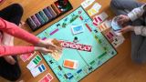 2 Spieler mit Spielgeld in den Händen spielen das Brettspiel Monopoly am Boden